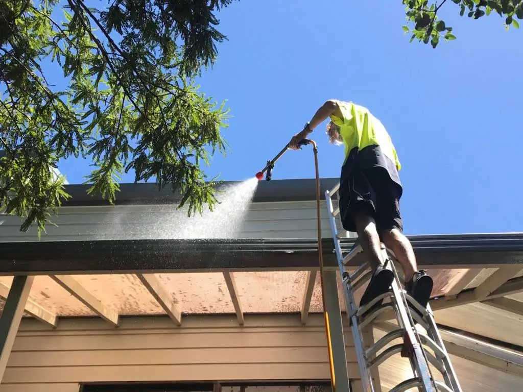 Roofer cleaning a house roof