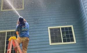 a team member from NJM Roof & Gutter cleaning doing a pressure wash to a home in Oregon