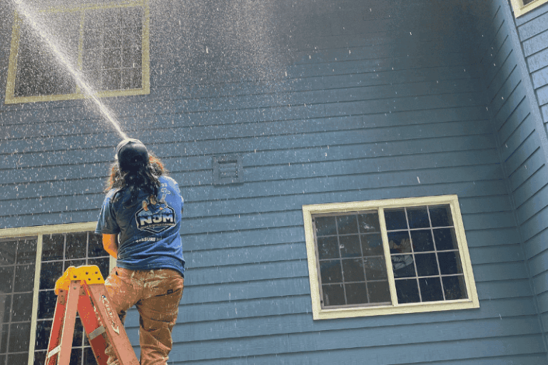 NJM team member pressure washing a house