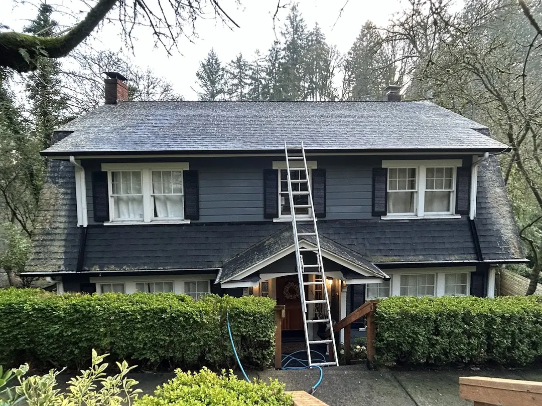 The same house after cleaning, with the moss gone from the main roof and the shingles an even dark gray